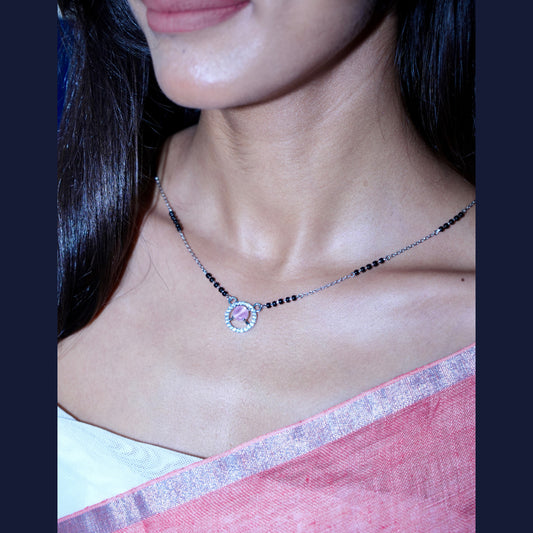 Necklace with a pink heart pendant worn by a person in a pink saree.