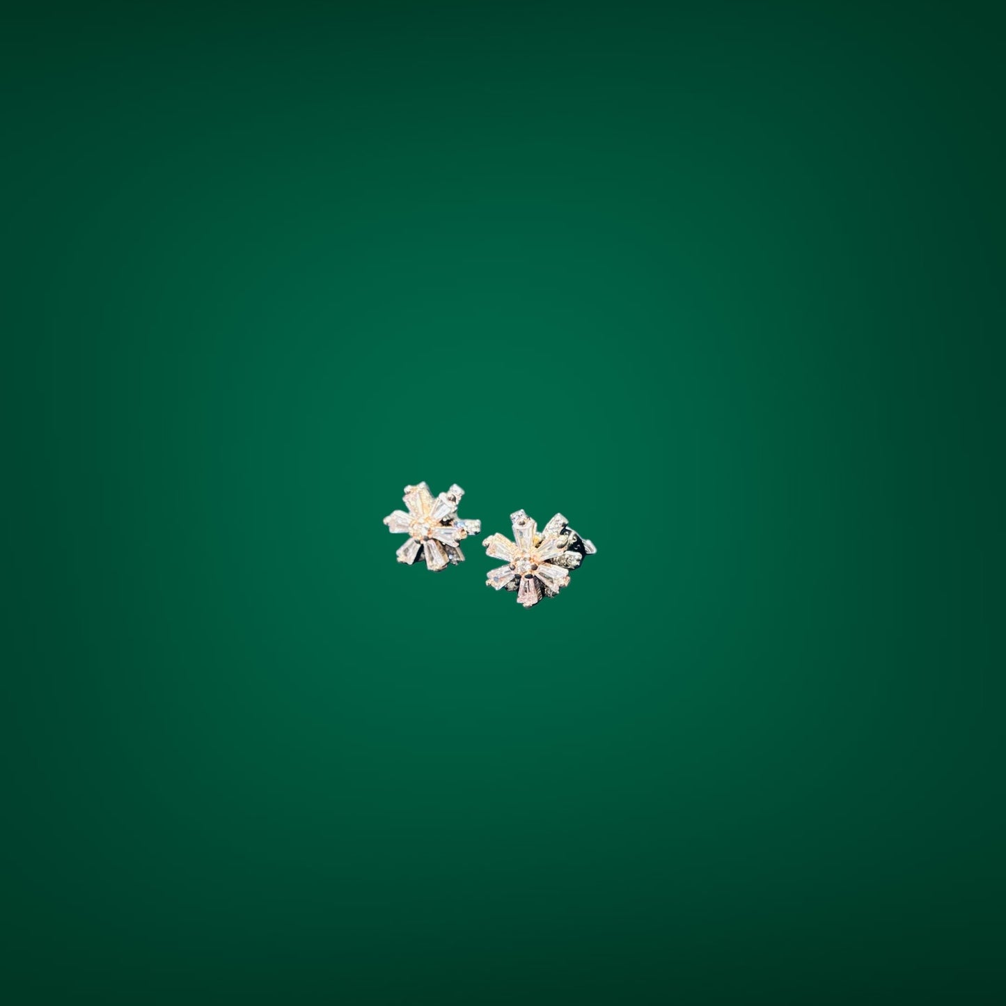 Pair of silver flower-shaped earrings on a green background
