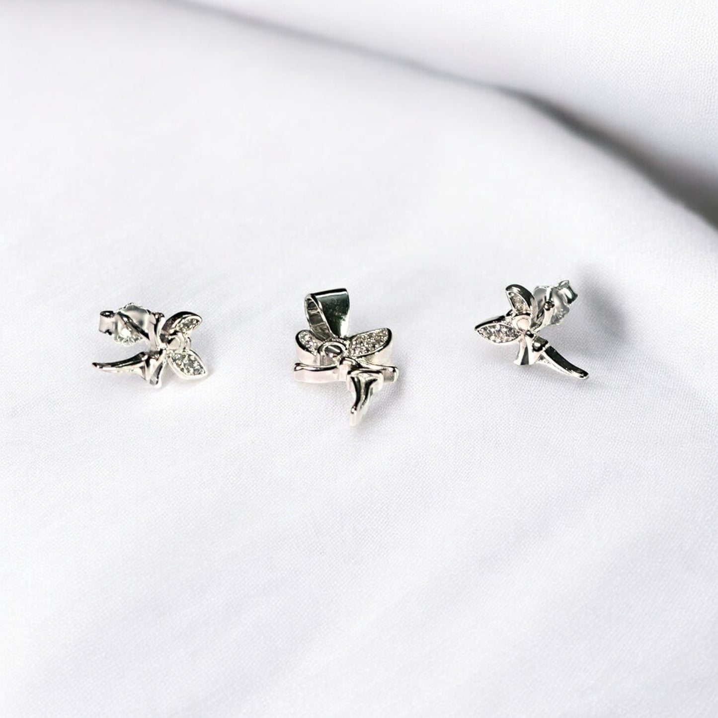 Three silver fairy-shaped earrings on a white surface