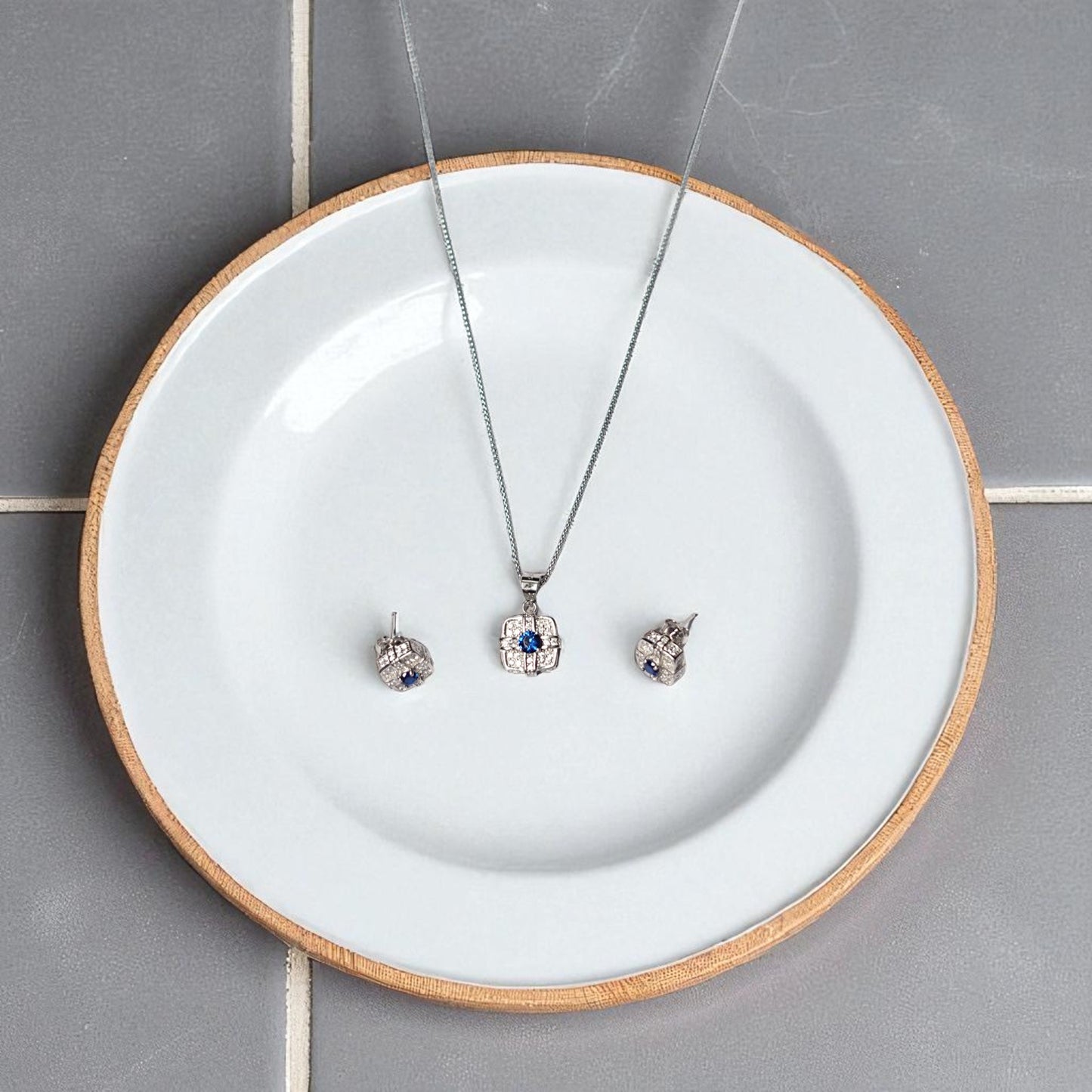 Jewelry set including a necklace and earrings on a white plate with wooden rim.