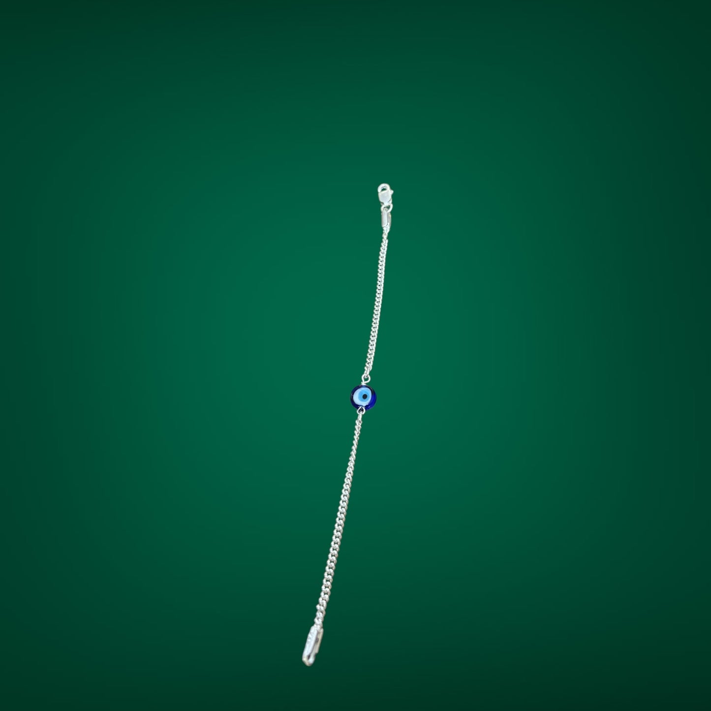 Silver bracelet with a blue bead on a green background