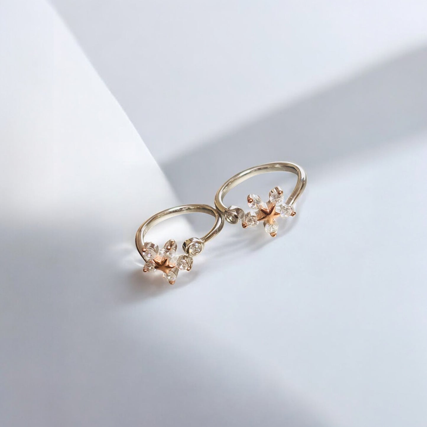Pair of gold earrings with floral designs on a light gray background