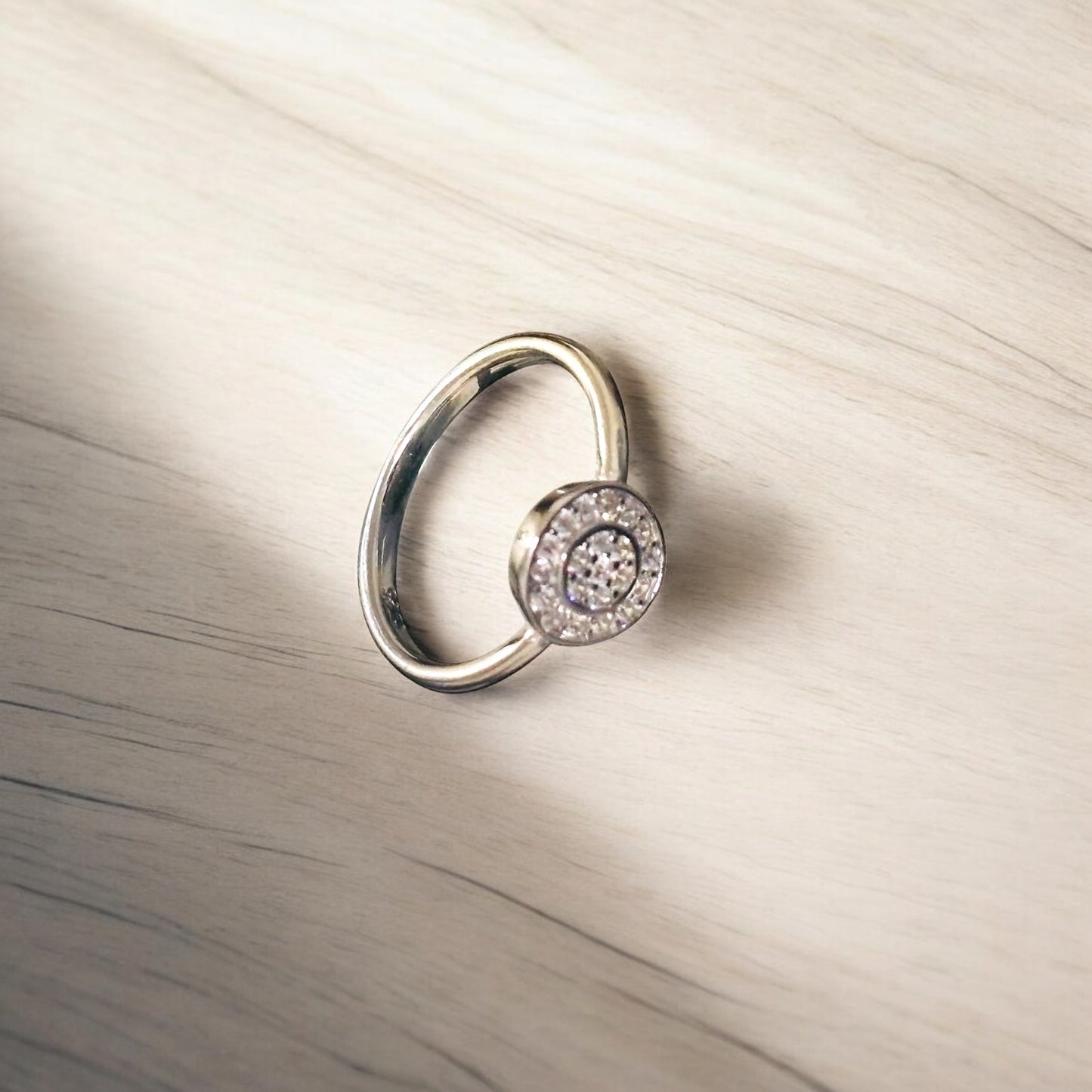 Silver ring with a circular design on a beige background