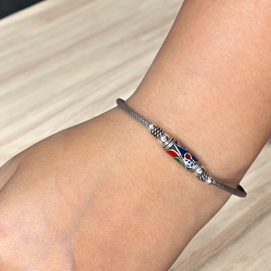 Bracelet with a colorful bead on a wrist against a neutral background