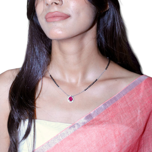 Woman wearing a necklace with a red gemstone on a white background