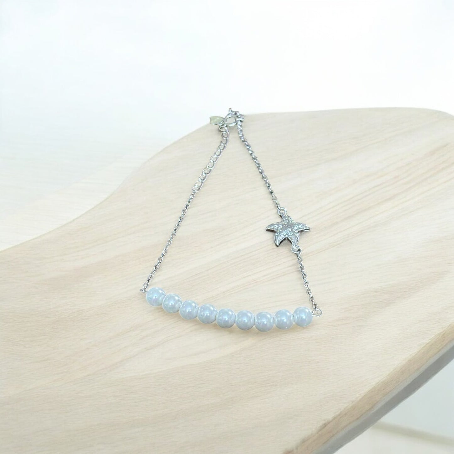 Starfish bracelet with beaded chain on a wooden surface