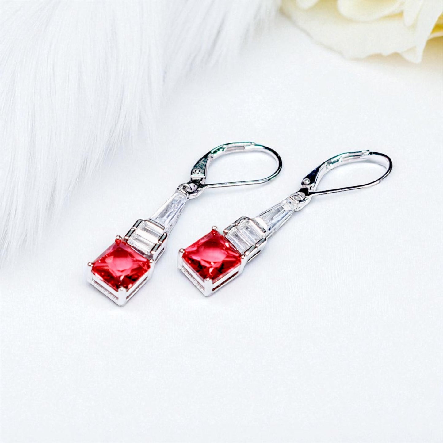 Silver earrings with red gemstones on a white background