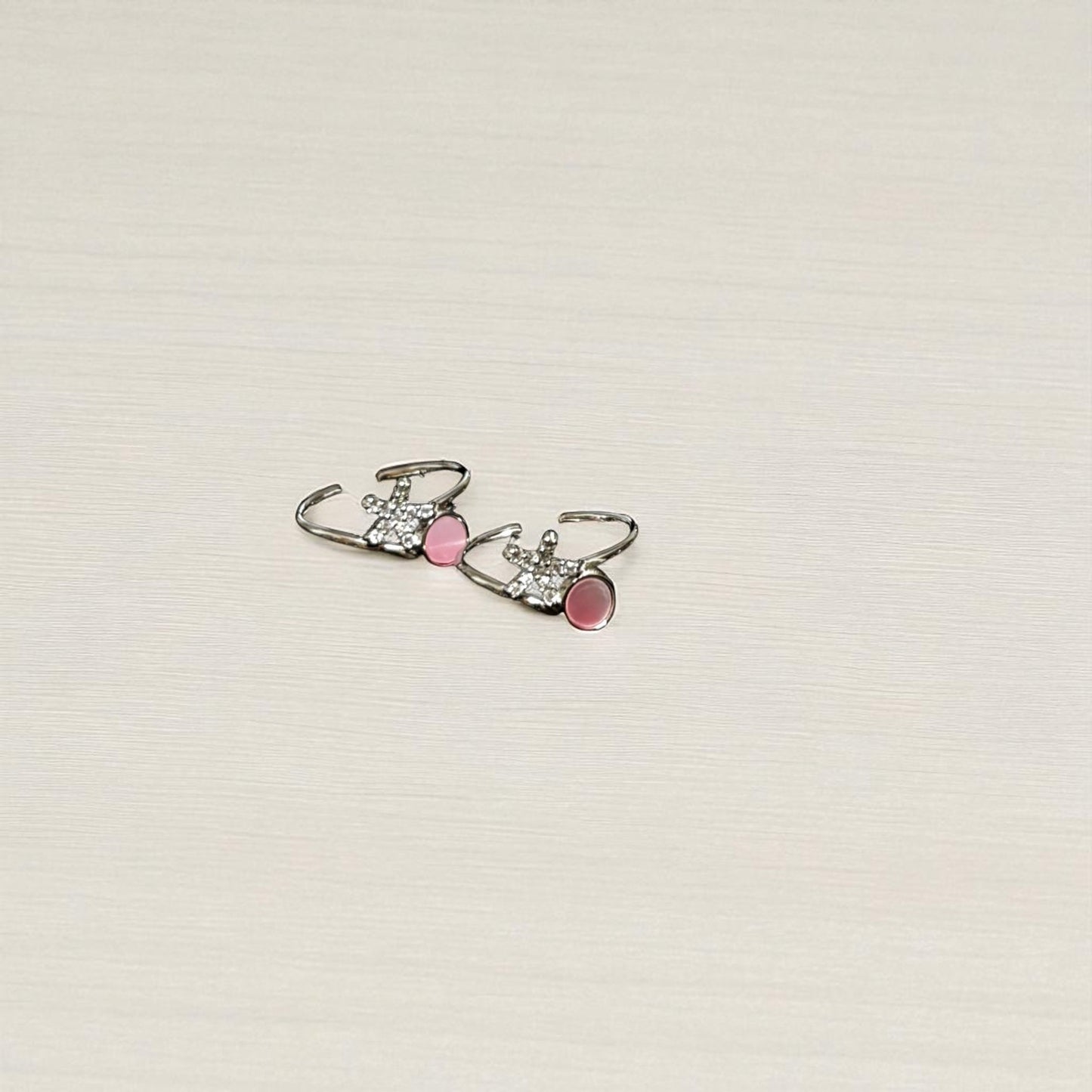 Pair of earrings with pink accents on a light beige background