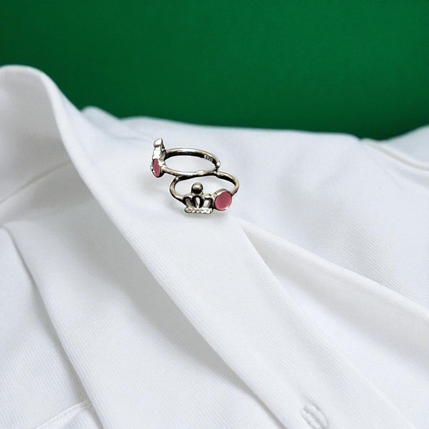 Silver ring with pink gemstones on a white fabric background