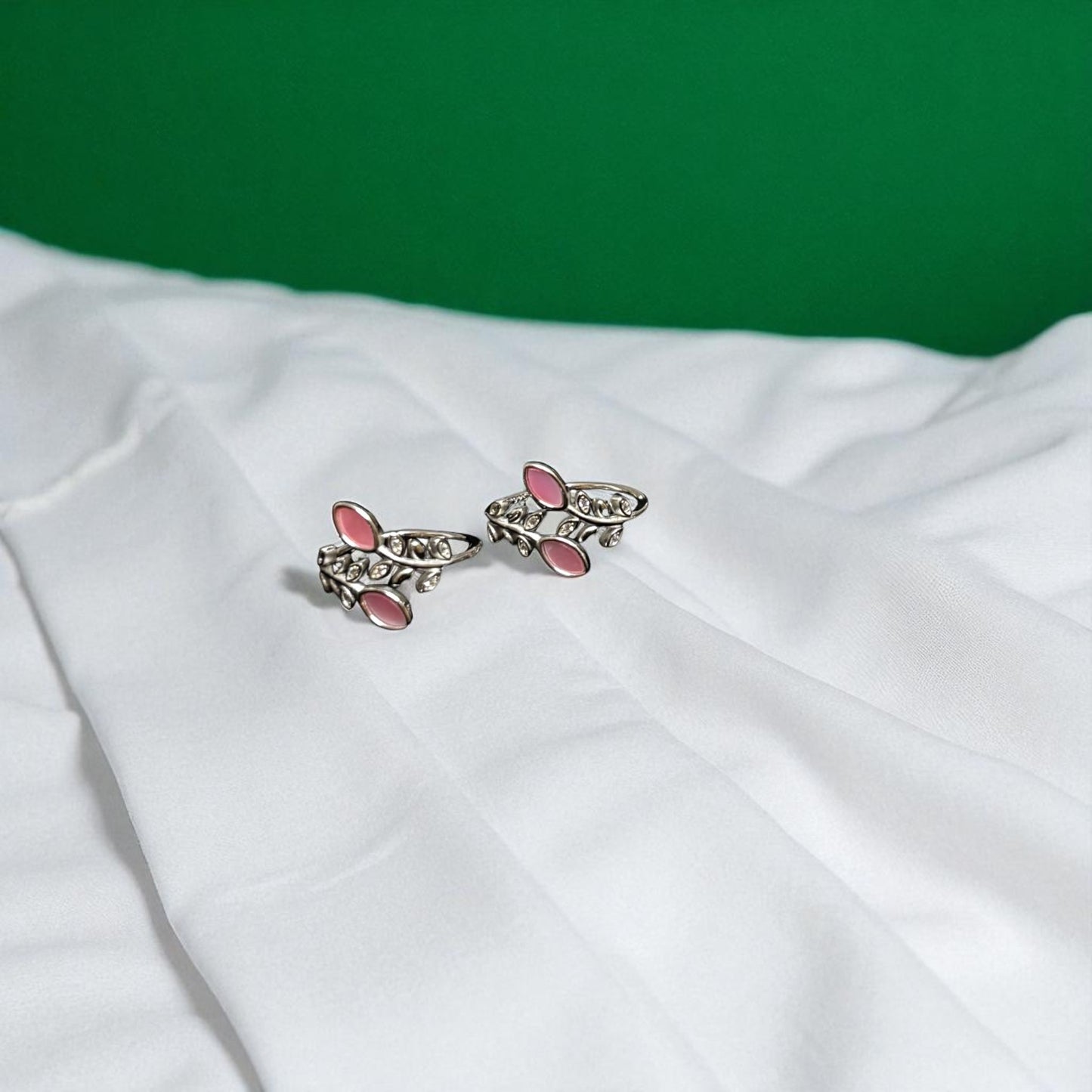 Butterfly-shaped earrings with pink centers on a white fabric background