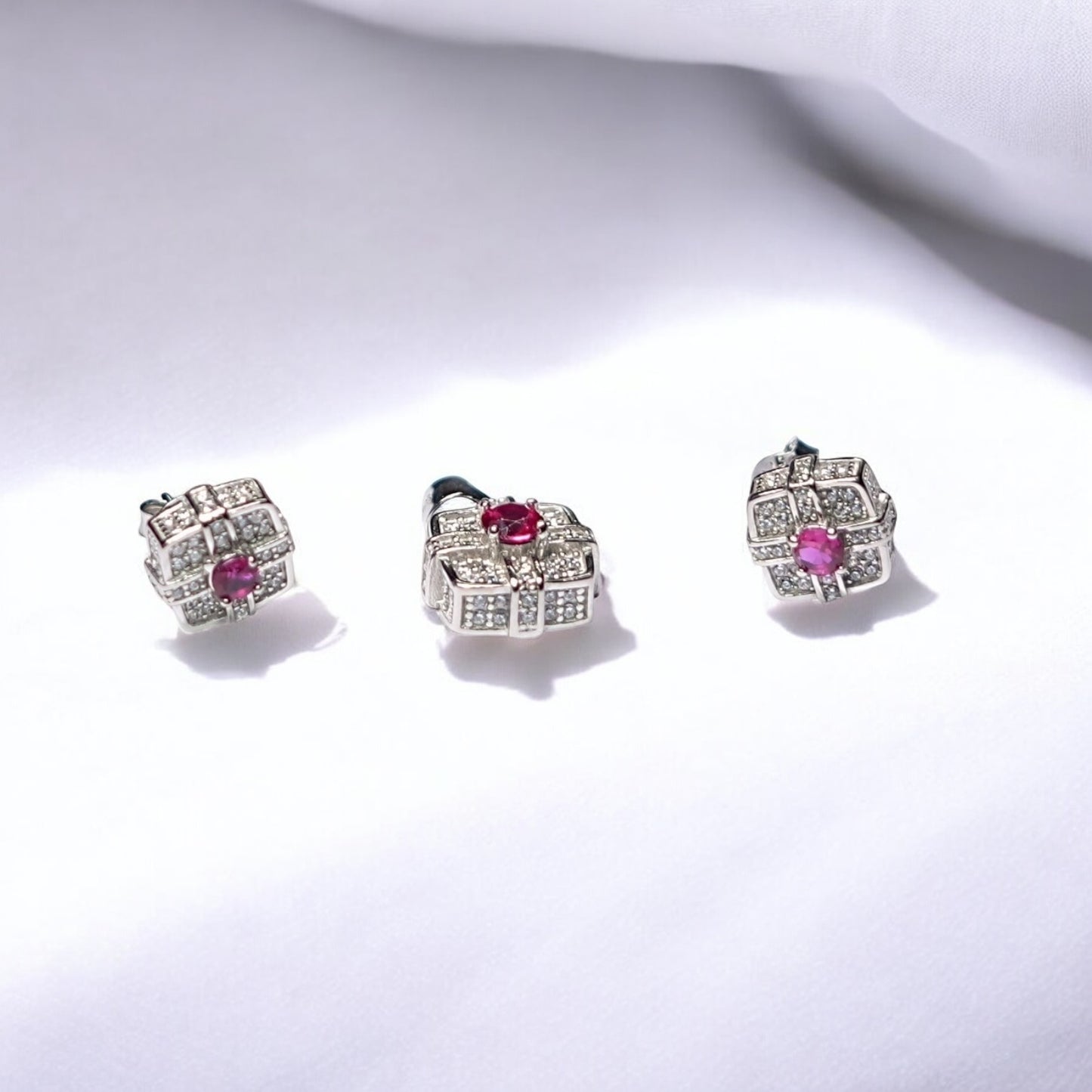 Pair of silver earrings with pink gemstones on a white background