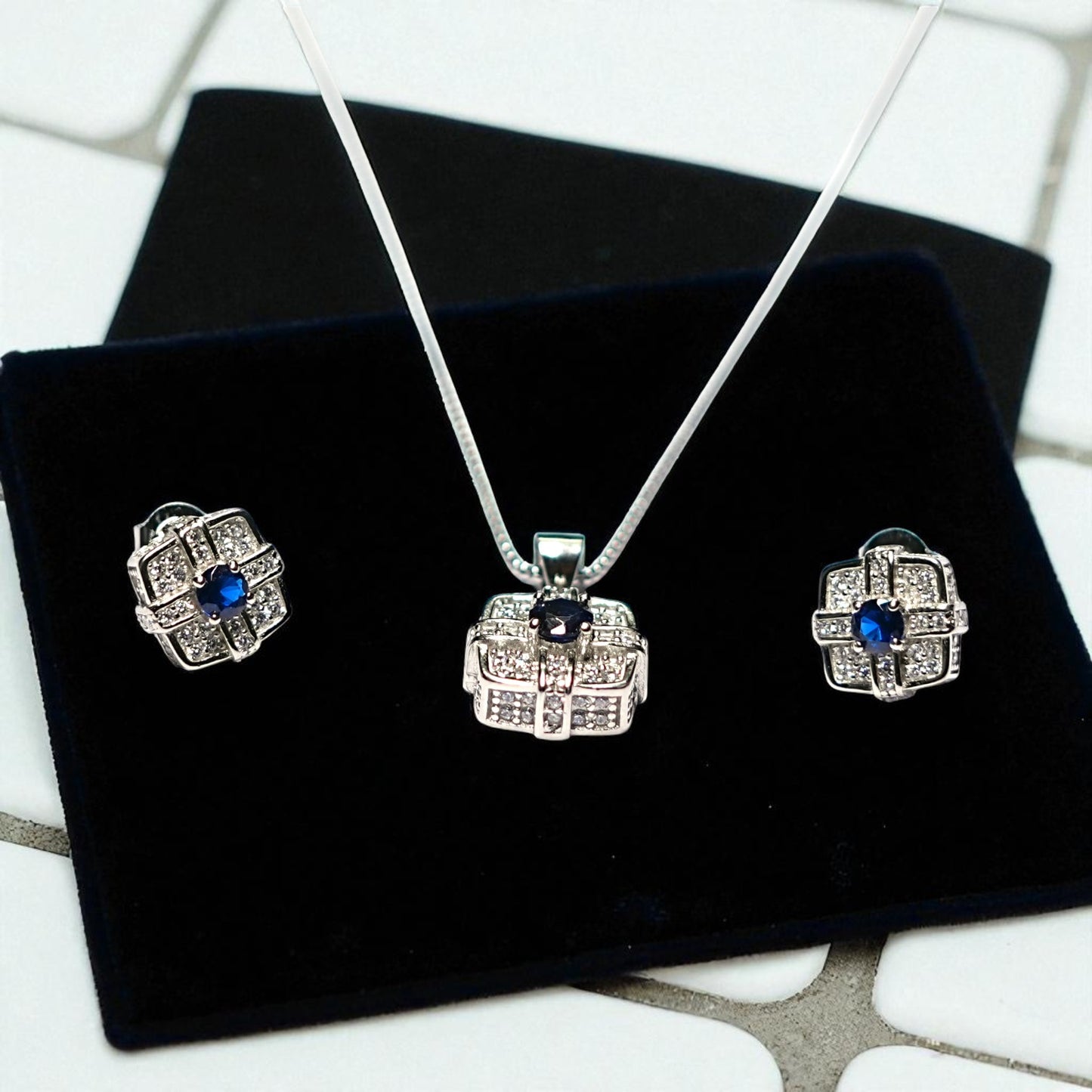 Silver jewelry set with blue stones on a black velvet surface