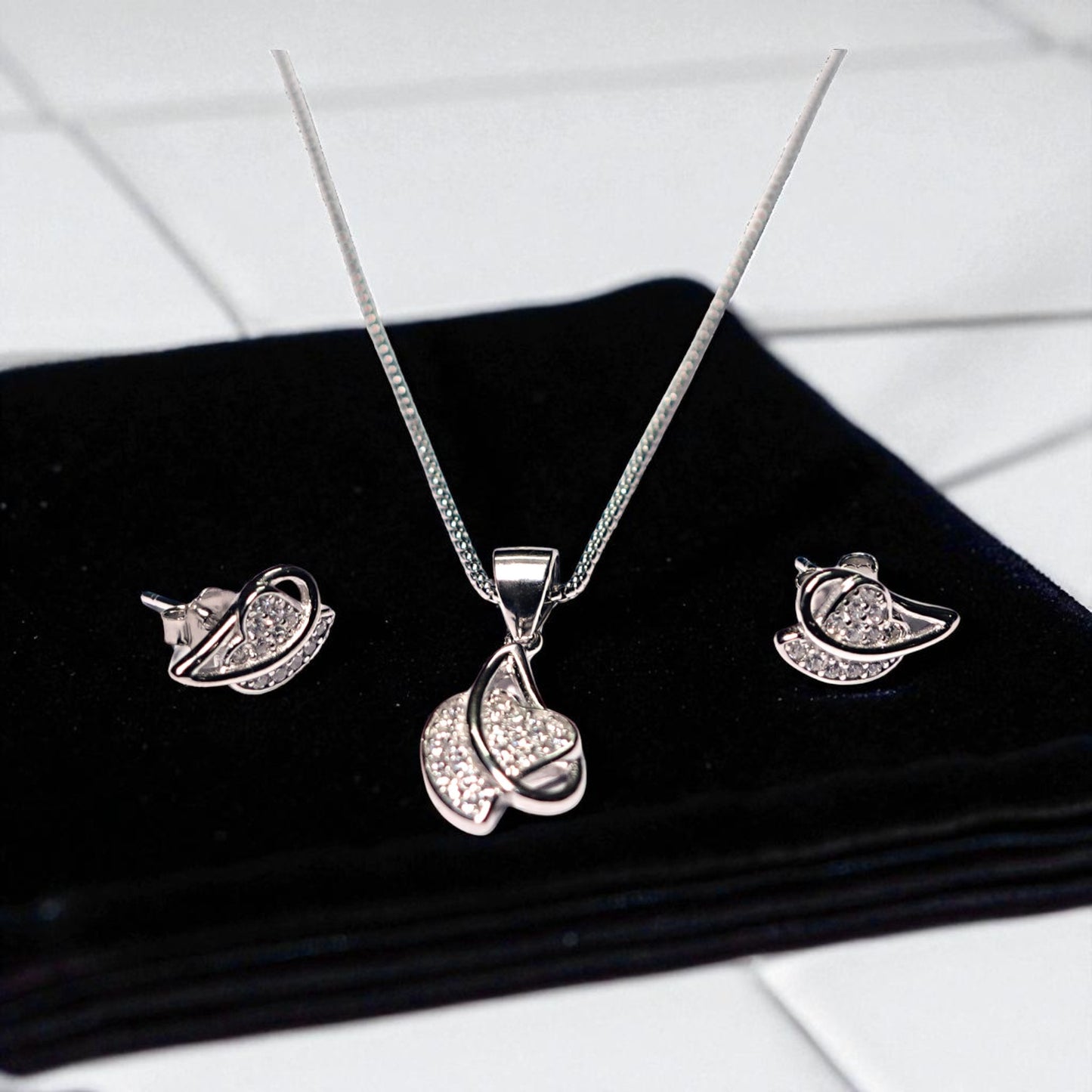 Silver jewelry set with necklace and earrings on a black surface