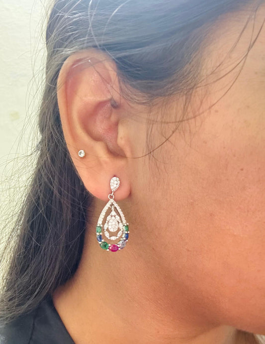 Close-up of an ear wearing a colorful teardrop earring with a blurred background