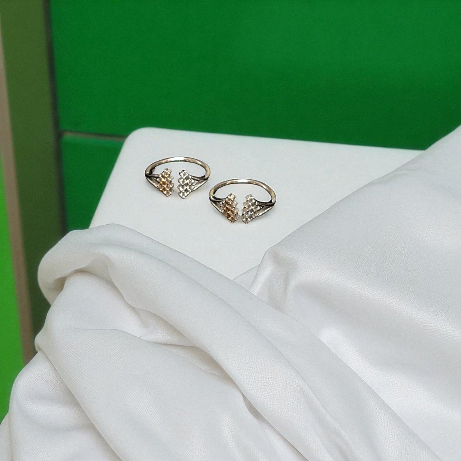 Pair of gold earrings on a white surface with a green background