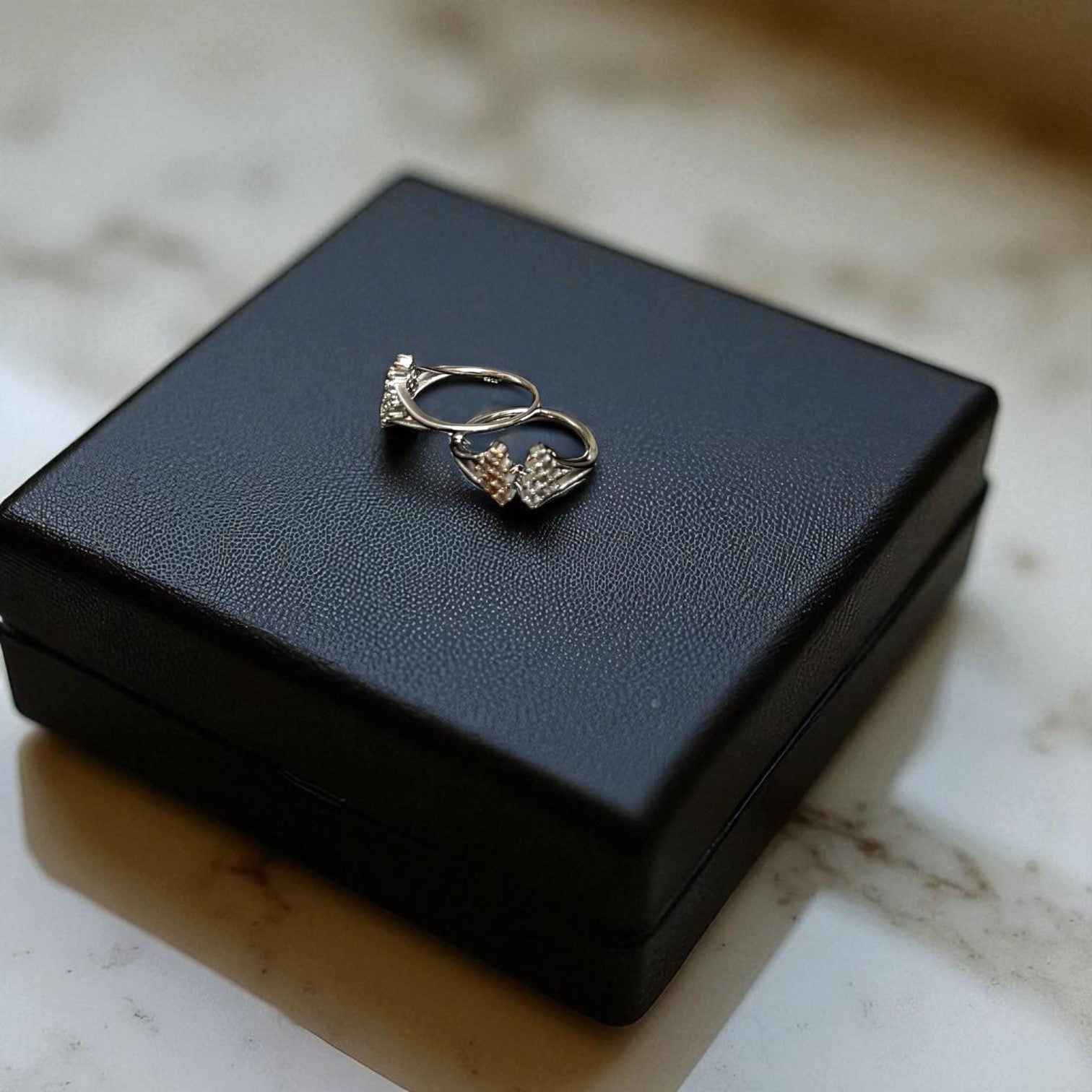 Pair of earrings on a black jewelry box with a marble background