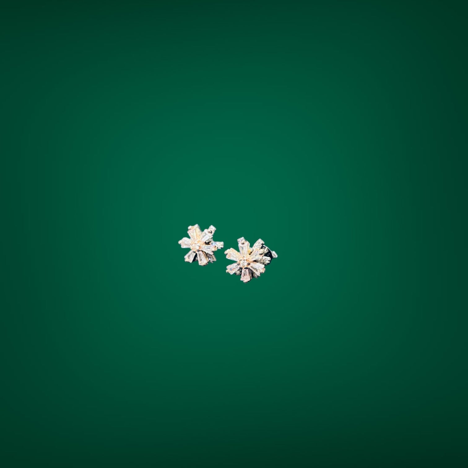 Pair of silver flower-shaped earrings on a green background