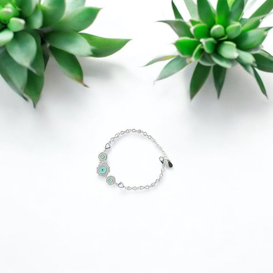 Silver bracelet with green stones on a white background with succulents