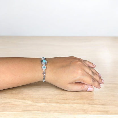 Hand wearing a bracelet on a wooden surface with a light background