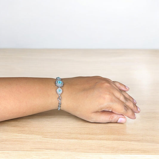 Hand wearing a bracelet on a wooden surface with a light background