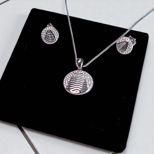 Silver jewelry set with pendant, necklace, and earrings on a black display stand.