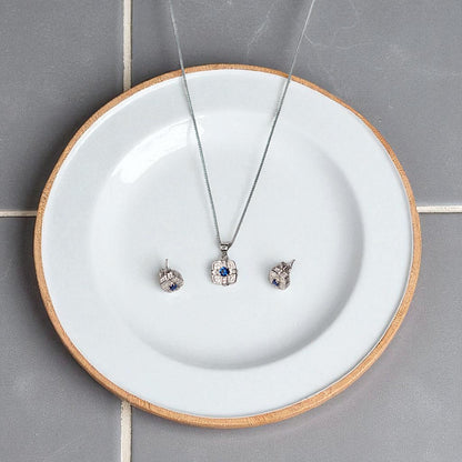 Jewelry set including a necklace and earrings on a white plate with wooden rim.