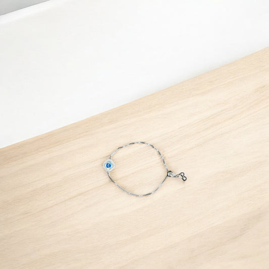 Silver bracelet with a blue evil eye charm on a wooden surface