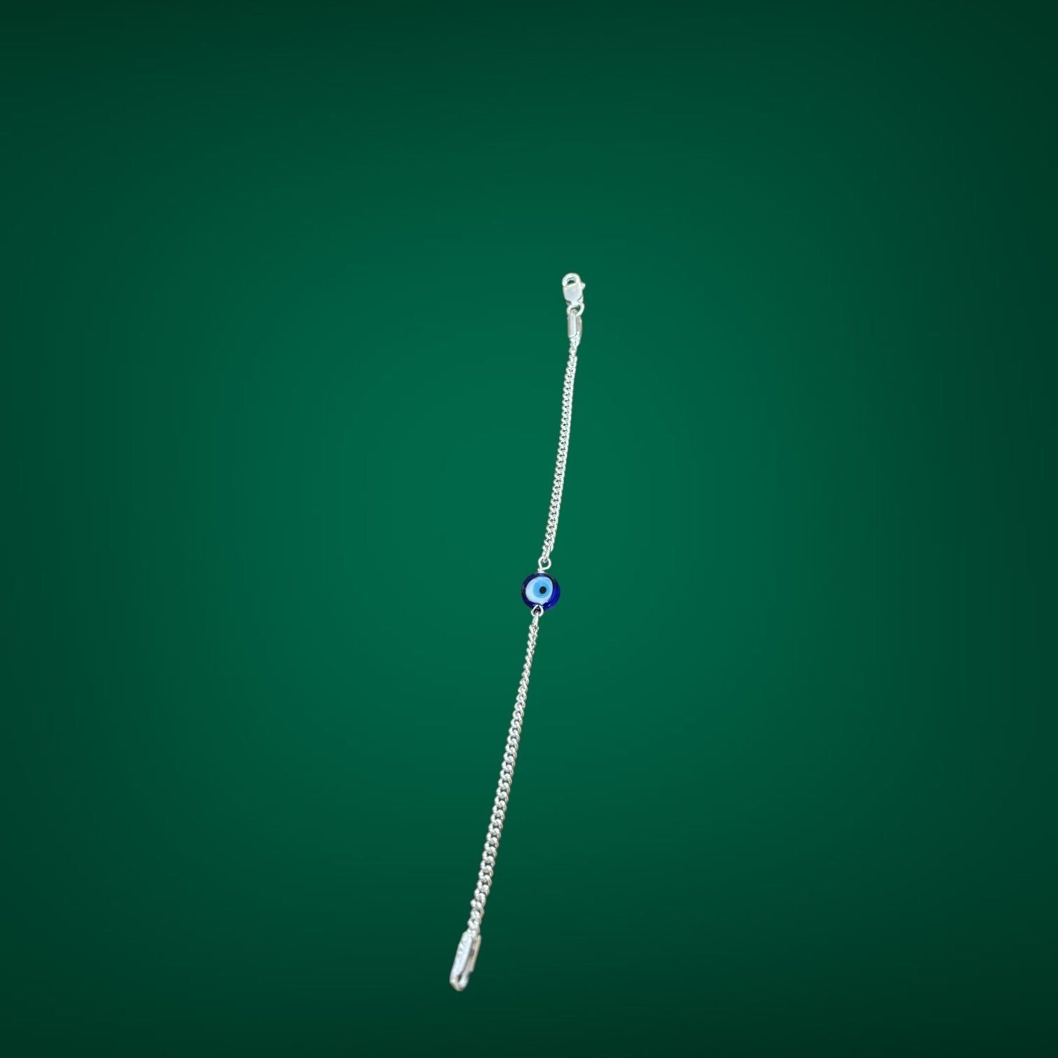 Silver bracelet with a blue bead on a green background