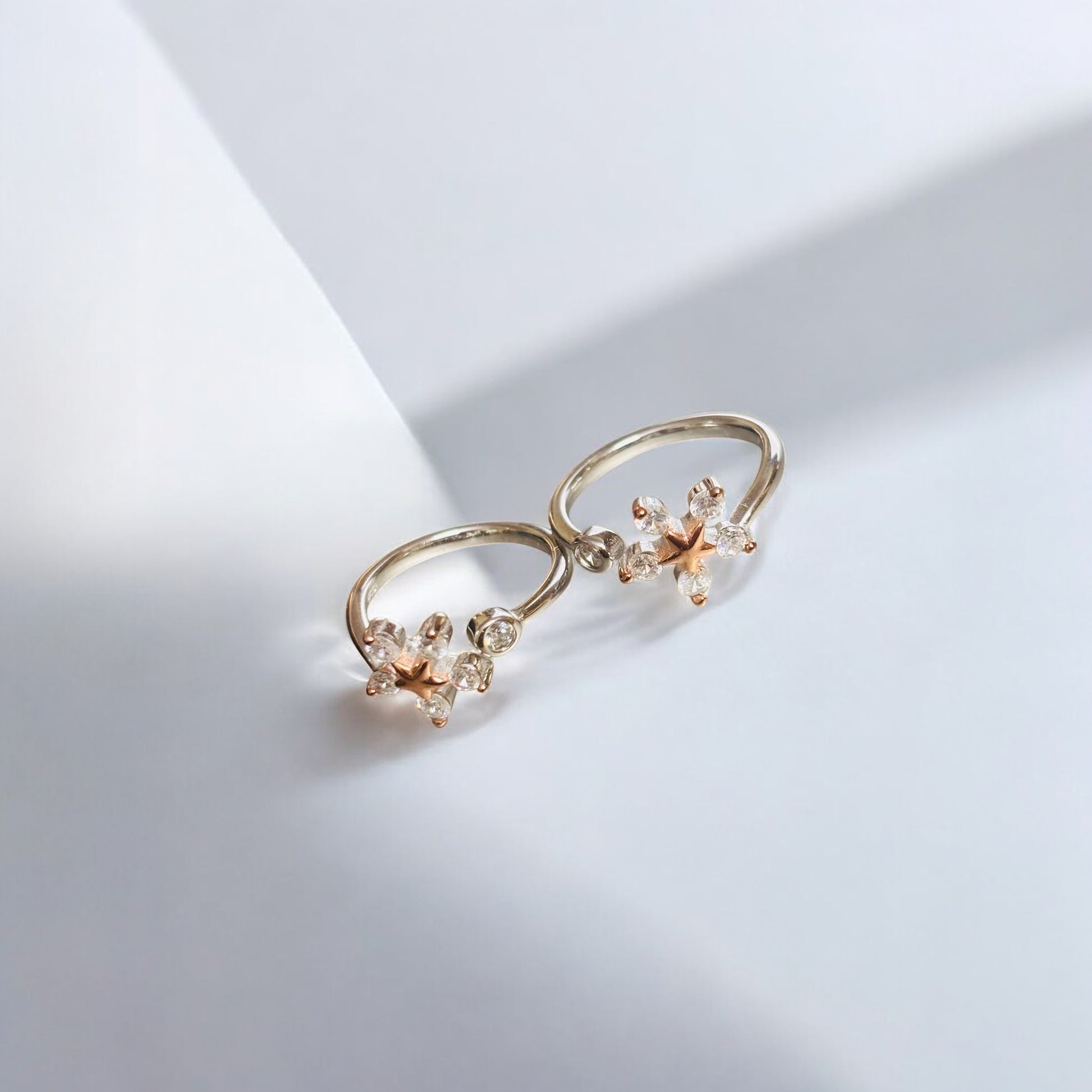 Pair of gold earrings with floral designs on a light gray background
