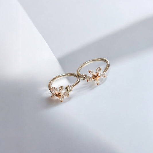 Pair of gold earrings with floral designs on a light gray background