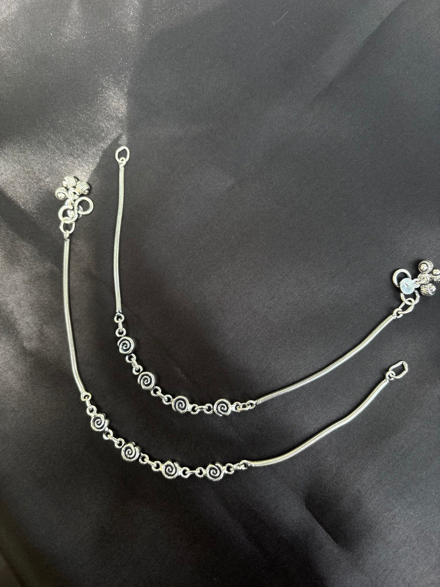 Silver bracelet with floral design on a dark fabric background