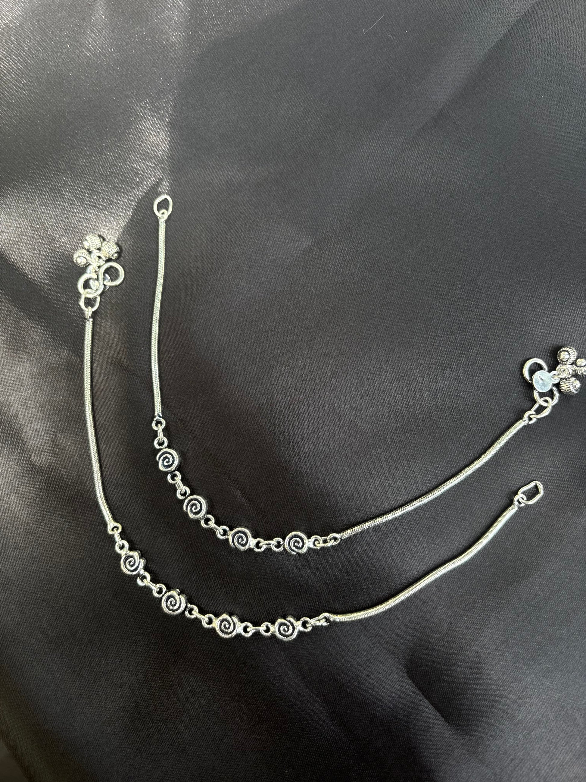 Silver bracelet with floral design on a dark fabric background