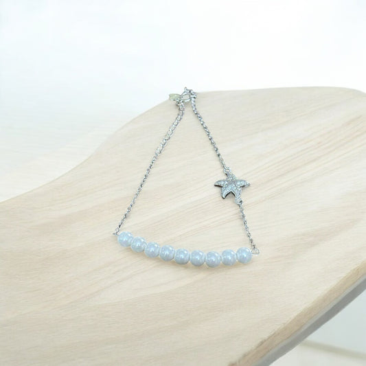 Starfish bracelet with beaded chain on a wooden surface