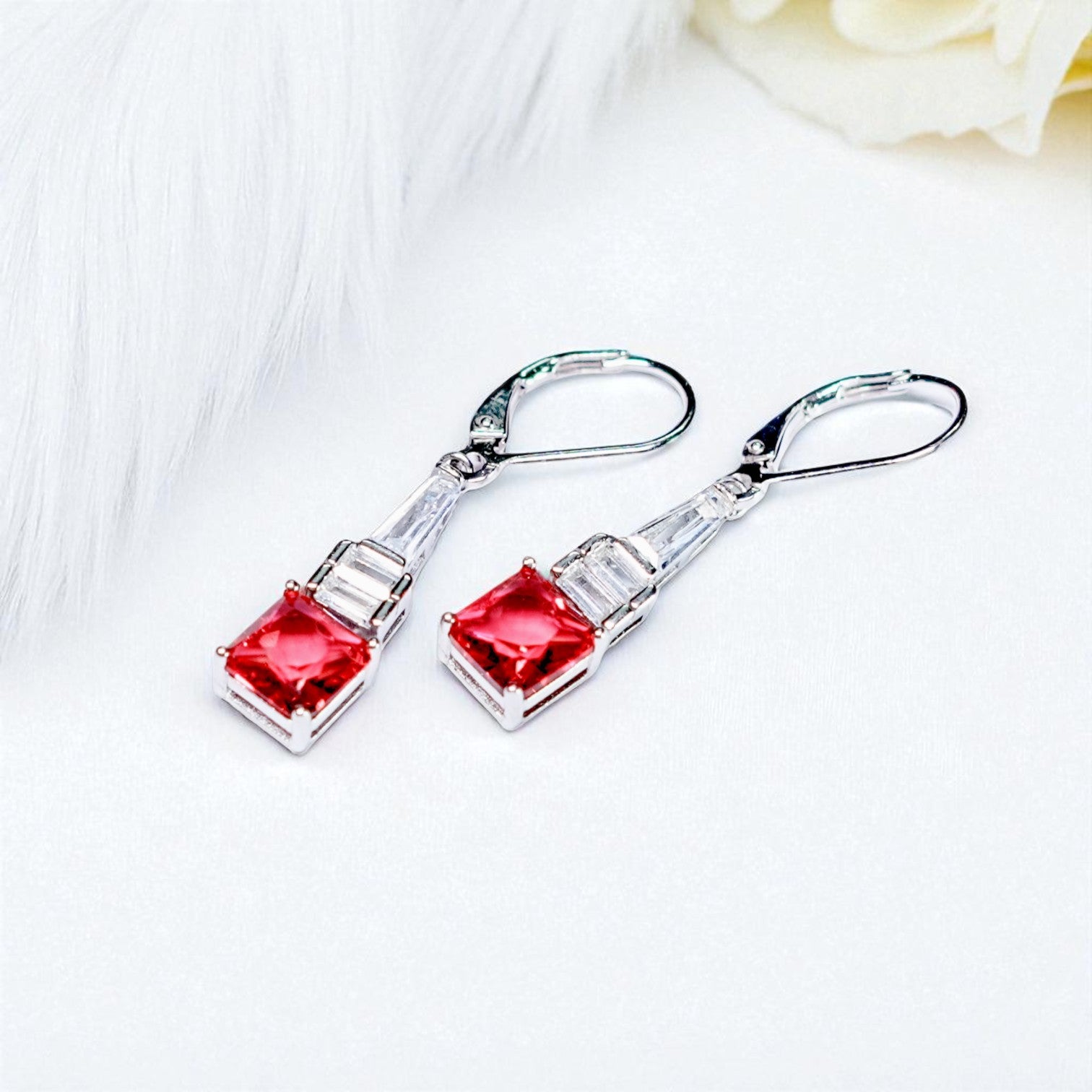 Silver earrings with red gemstones on a white background