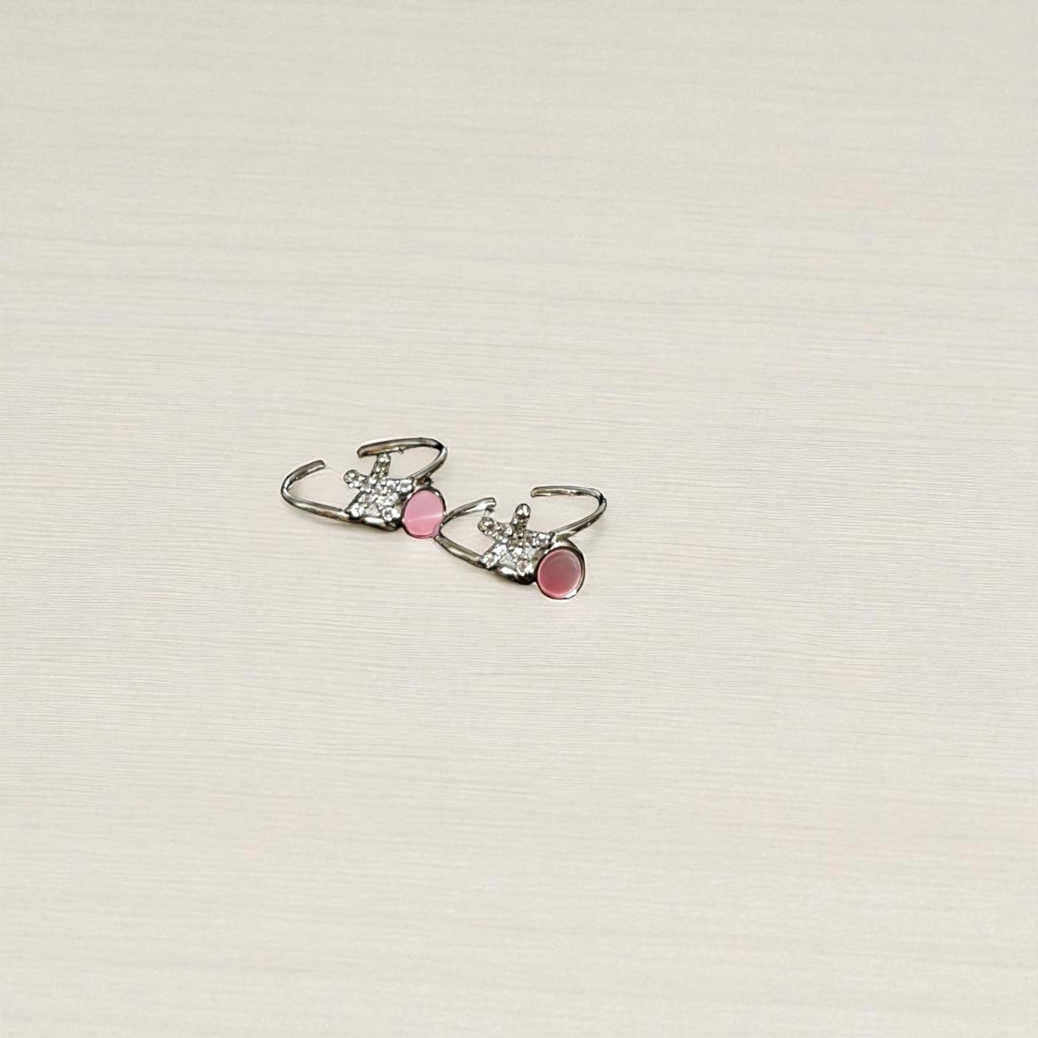 Pair of earrings with pink accents on a light beige background