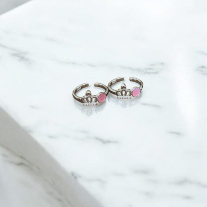 Two silver rings with pink gemstones on a marble surface