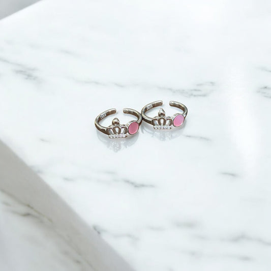 Two silver rings with pink gemstones on a marble surface