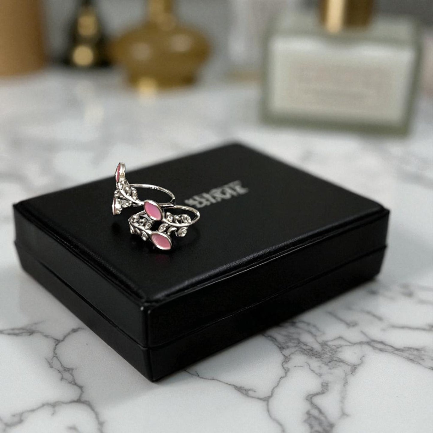 Silver and pink ring on a black jewelry box with 'Buccellati' branding on a marble surface.