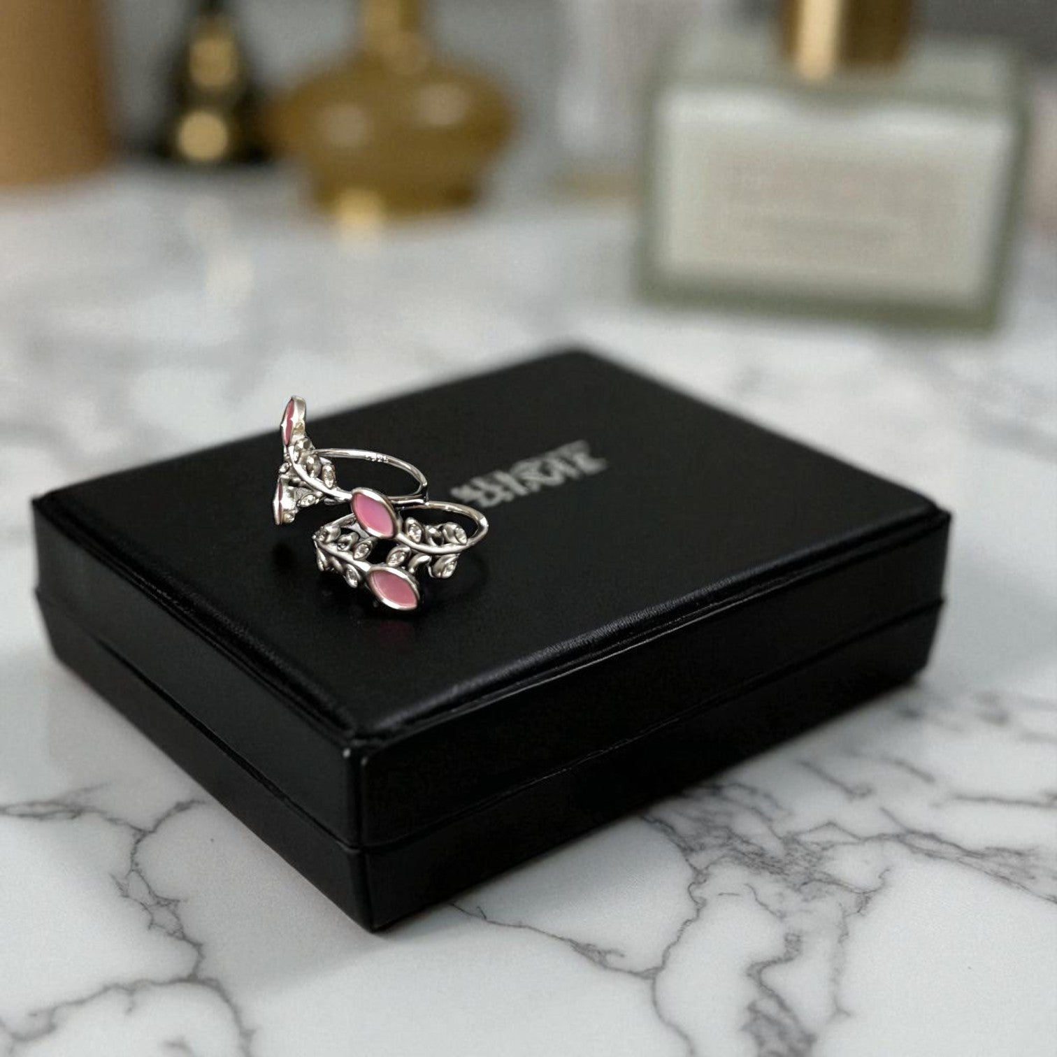 Silver and pink ring on a black jewelry box with 'Buccellati' branding on a marble surface.