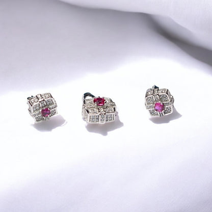 Pair of silver earrings with pink gemstones on a white background
