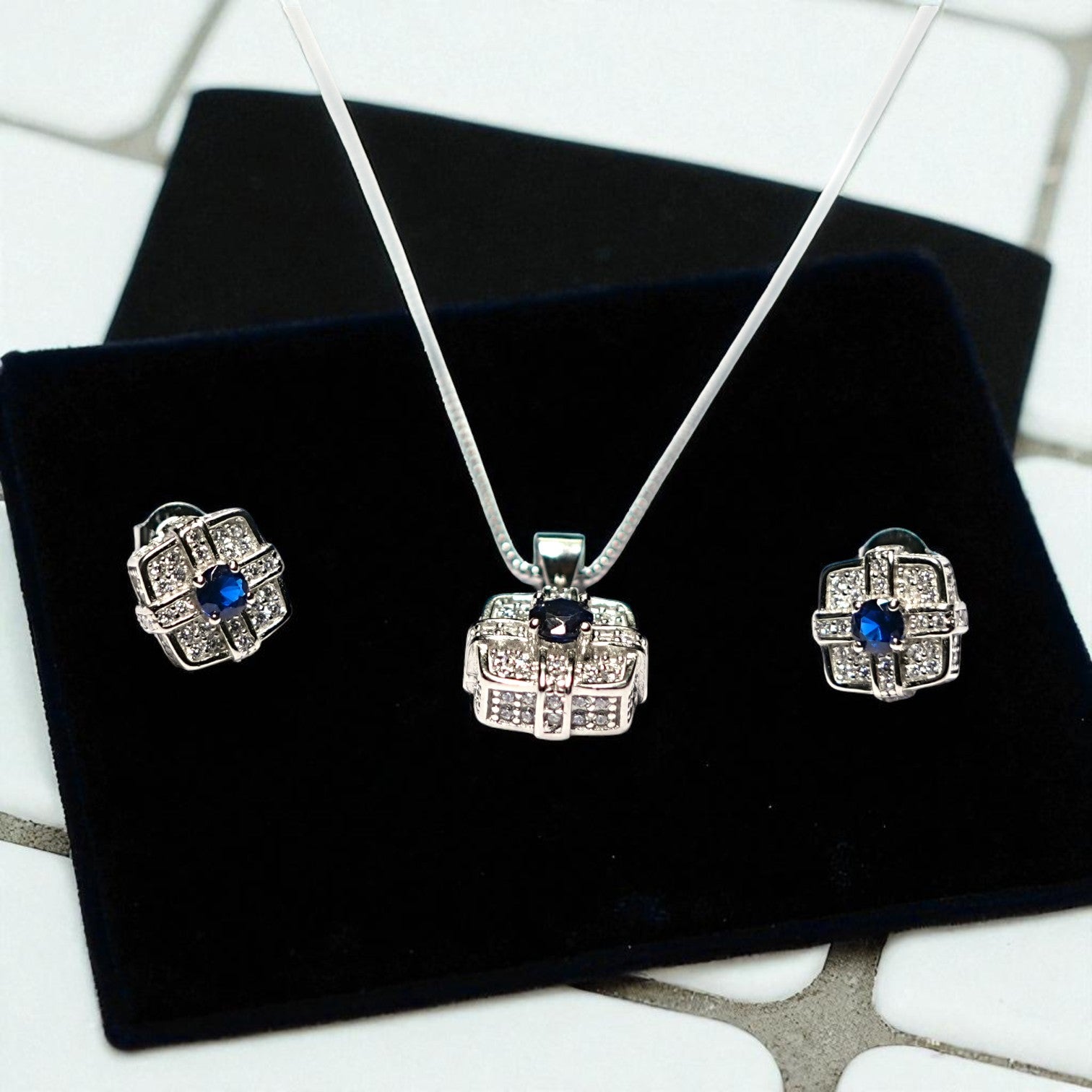Silver jewelry set with blue stones on a black velvet surface