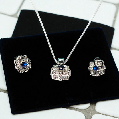 Silver jewelry set with blue stones on a black velvet surface