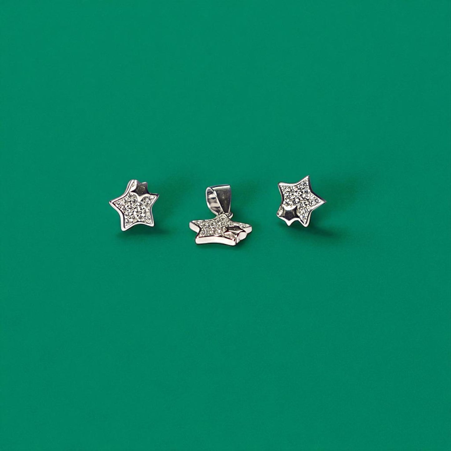 Three star-shaped silver earrings on a green background