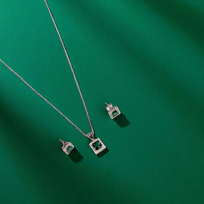 Jewelry set with square emerald stones on a green background