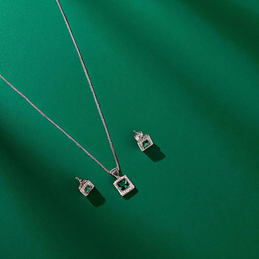 Jewelry set with square emerald stones on a green background