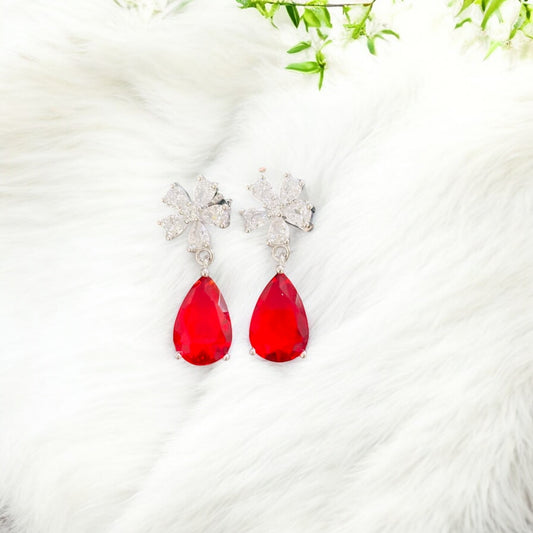 Red teardrop earrings with silver floral tops on a white background