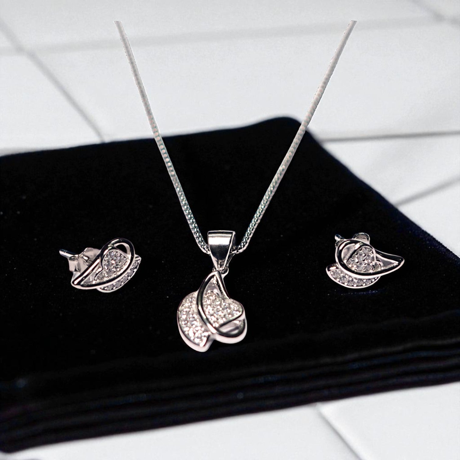 Silver jewelry set with necklace and earrings on a black surface