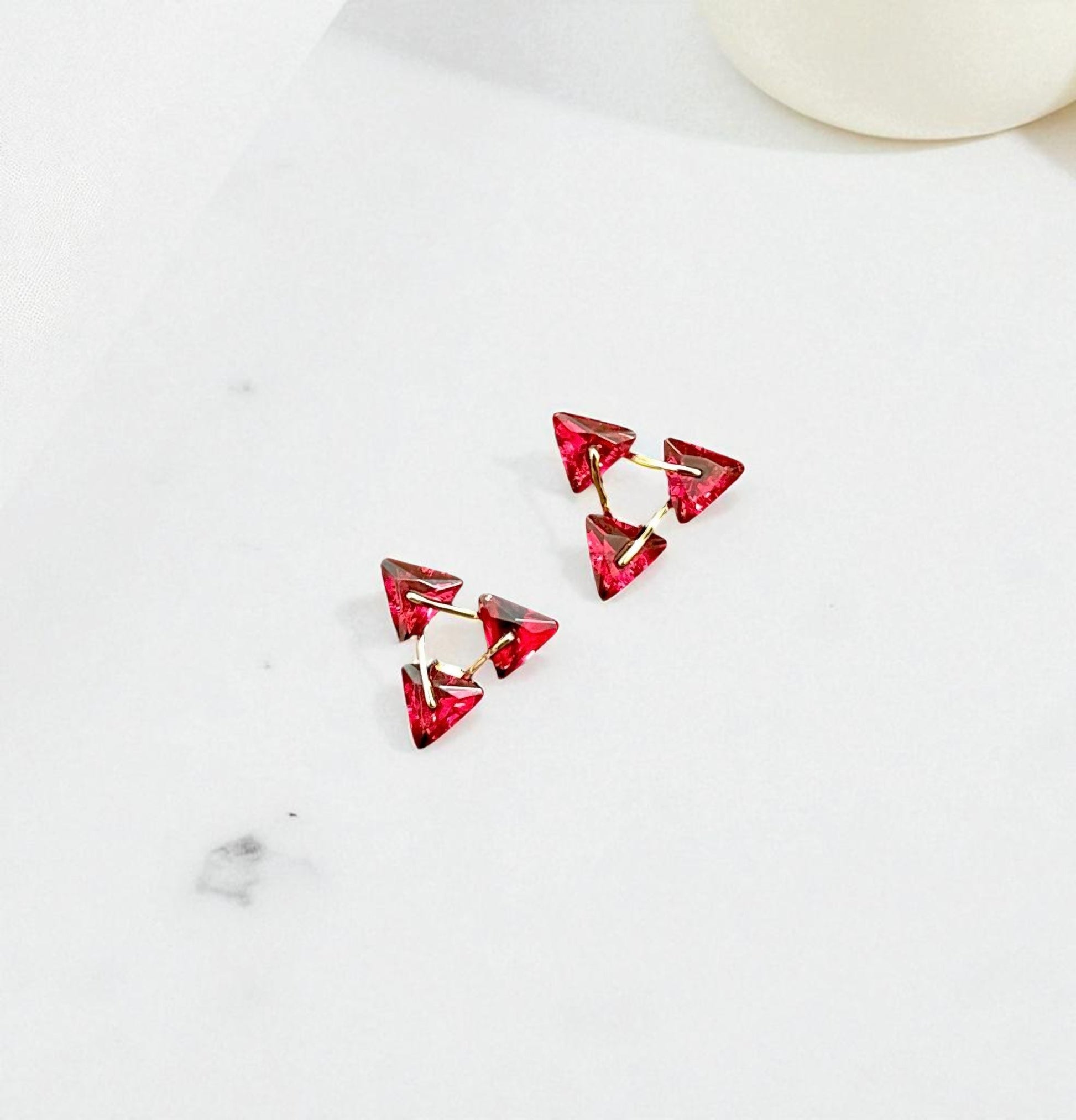 Red triangular earrings on a white background